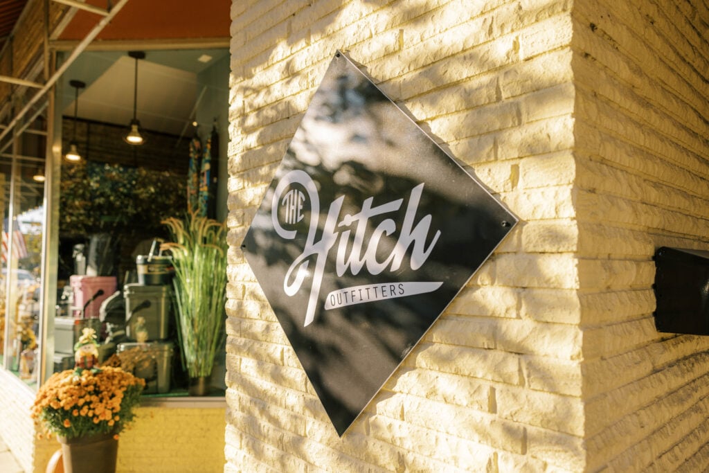 The exterior storefront and iconic hanging sign of The Hitch Outfitters, an outdoor retail shop located in historic downtown McMinnville.