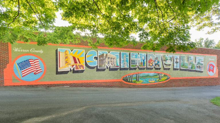 A large "postcard-style" mural on a brick wall featuring the letters of "McMinnville" filled with local landmarks, including the Park Theater and outdoor scenes.