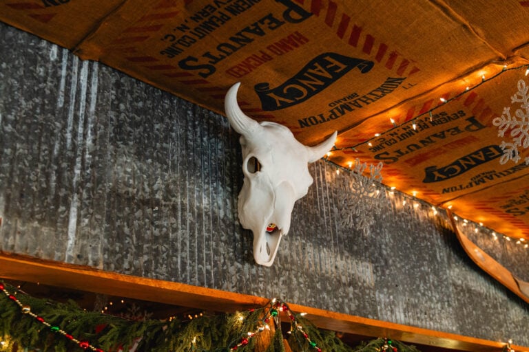 Unique interior decor at Foglight Foodhouse in Rock Island, TN, featuring a steer skull on a corrugated metal wall and a burlap sack ceiling.