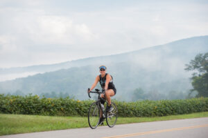 A cyclist riding along a scenic, tree-lined road on the BikeTN Rock Island Loop near McMinnville, Tennessee.