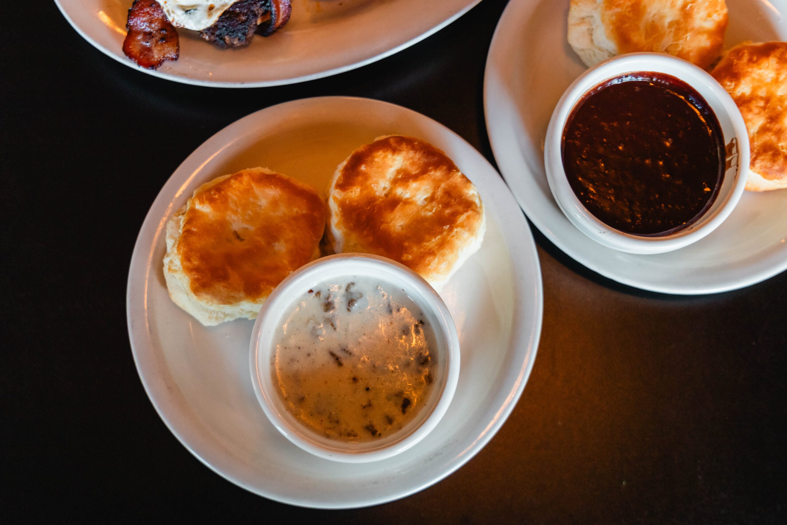 A golden-brown breakfast biscuit sandwich served on a plate in a cozy restaurant setting.
