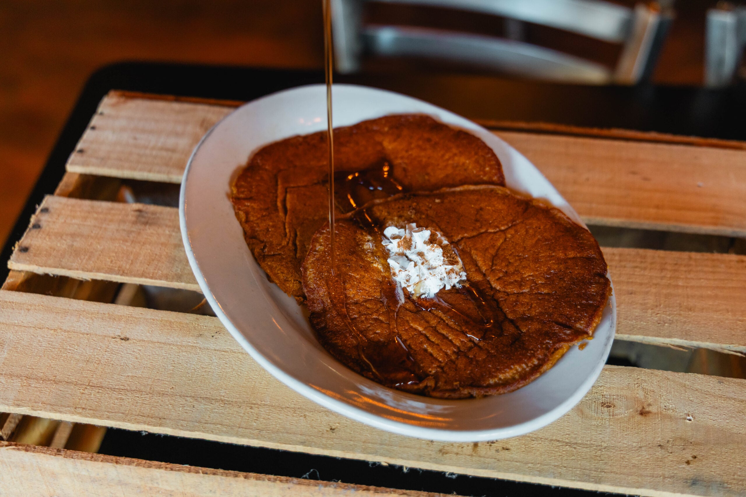 A tall stack of buttermilk pancakes topped with melting butter and syrup at Cumberland Biscuit Co.