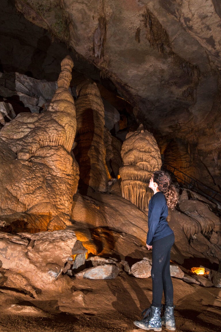 A young explorer admiring towering, ancient stalagmites inside Cumberland Caverns, showcasing the best caving in Tennessee.